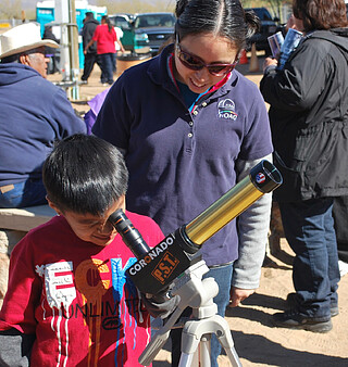 Child looking into space through a telescope